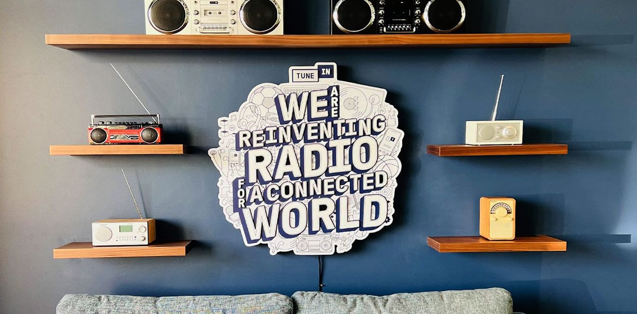 Tunein illuminated wall art in a retro style surrounded by the brand's iconic radios