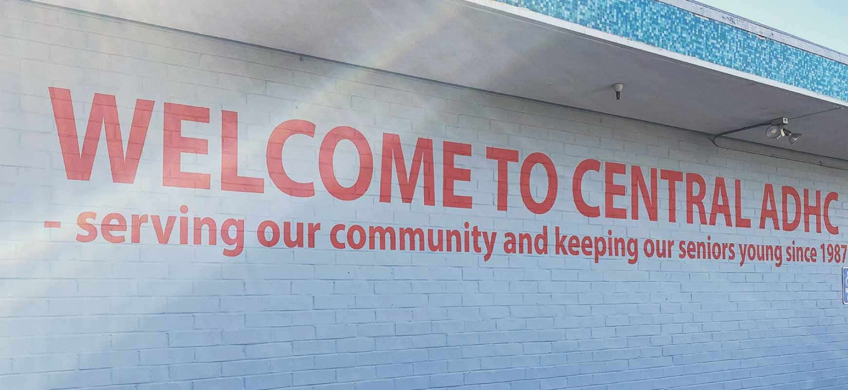 Adult Day Health Care community entrance signage painted in red for the exterior wall design