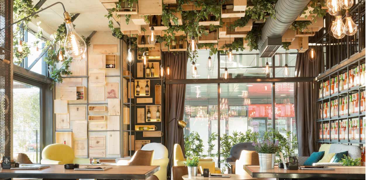 Fifth wall restaurant interior design trend wooden crates, greens and light bulbs
