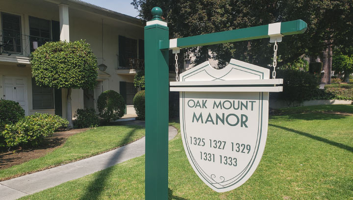 Oak Mount Manor HOA community entrance sign in a hanging style made of aluminum and plywood