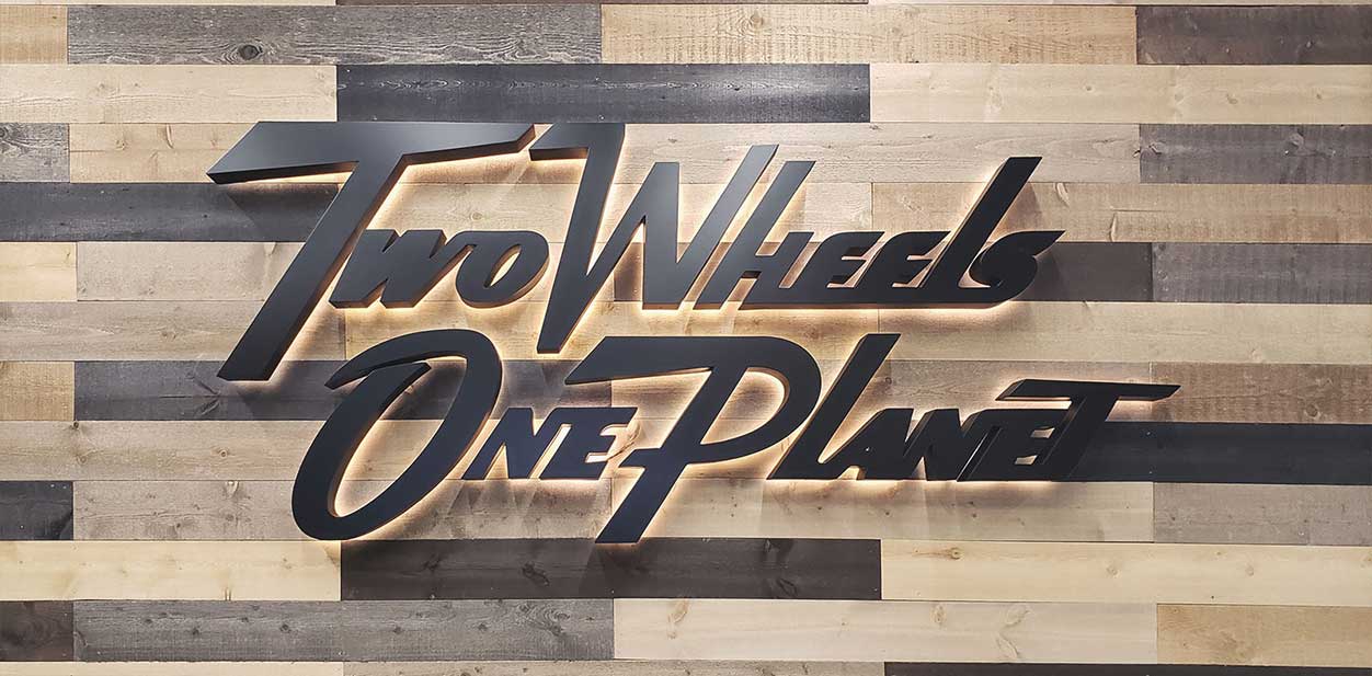 Two Wheels One Planet backlit wall art with wooden background for branding purposes