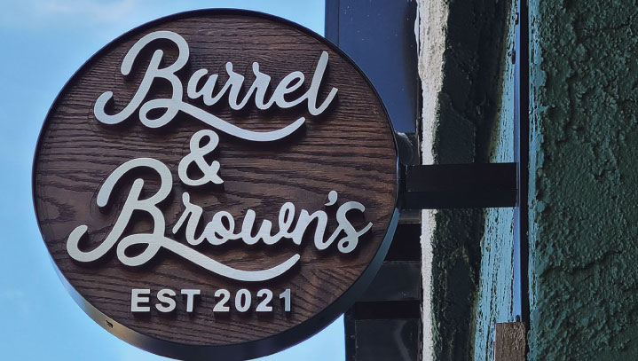 Barrel & Brown's wall signage reading the brand name made of plywood and brushed aluminum