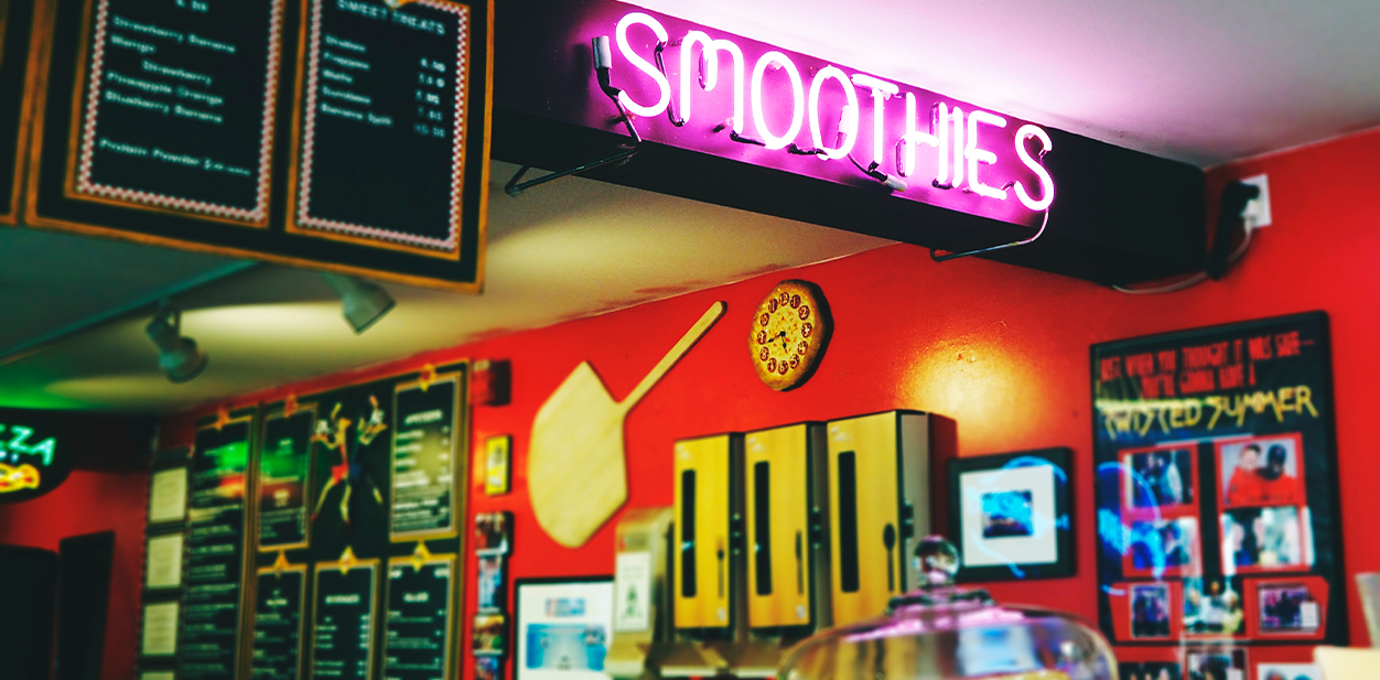 Retro retail store neon signage design in pink displaying the word Smoothies