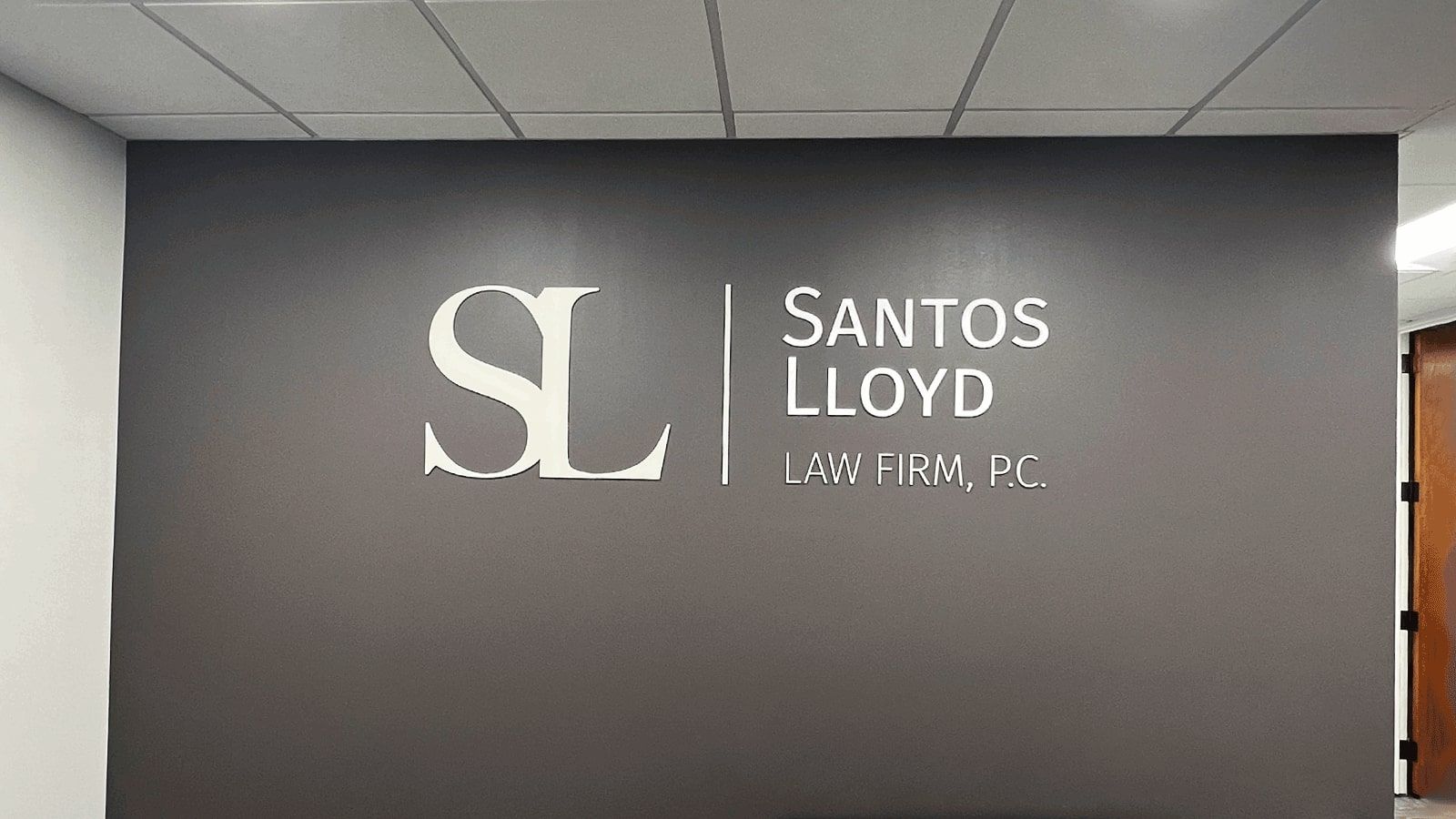 Santos Lloyd Law Firm, PC acrylic signs set up on the wall