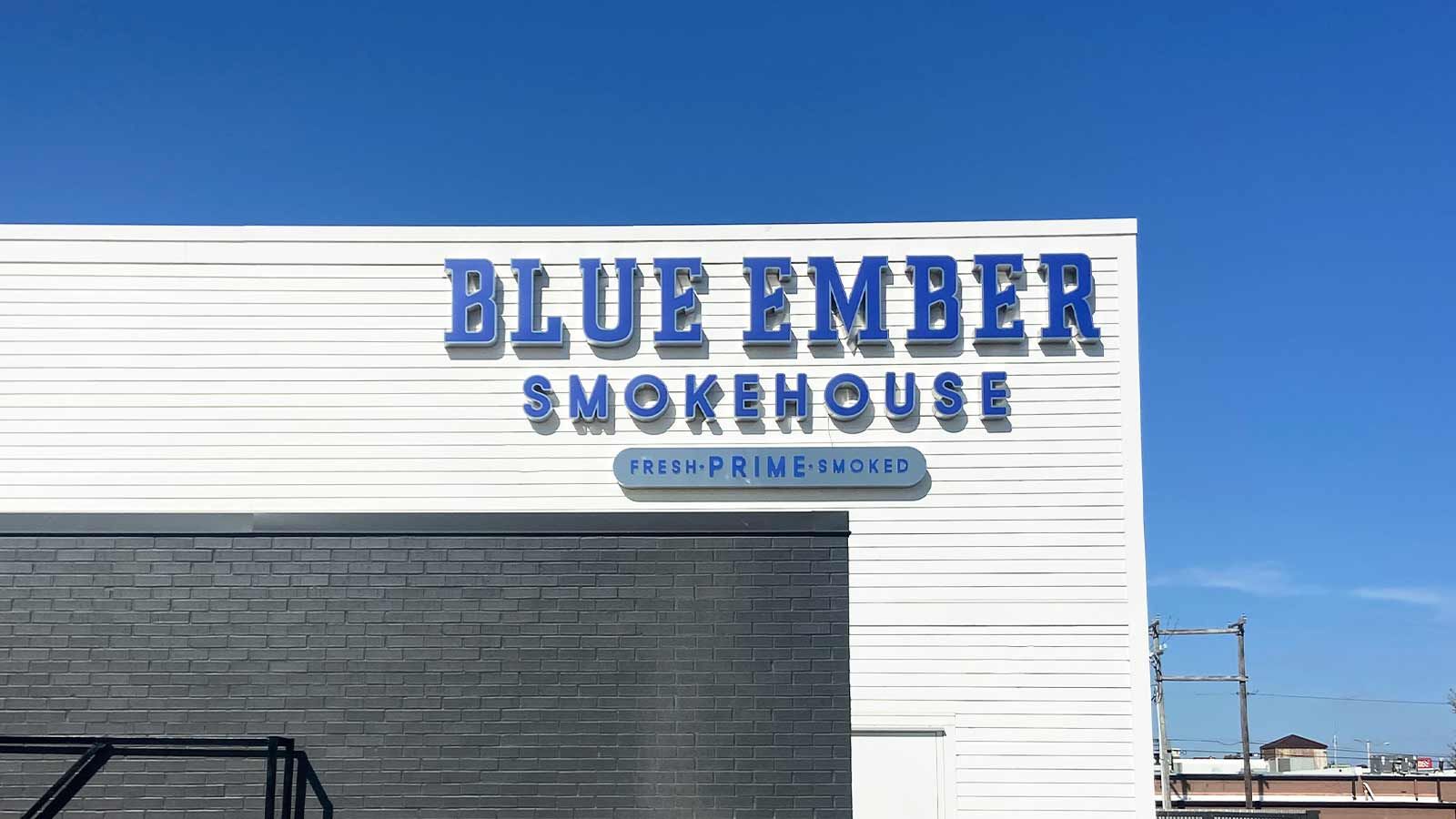 Blue Ember Smokehouse light up signs set up on building top