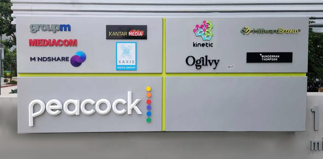 Peacock corporate branding design on a freestanding medium displaying multiple brand names