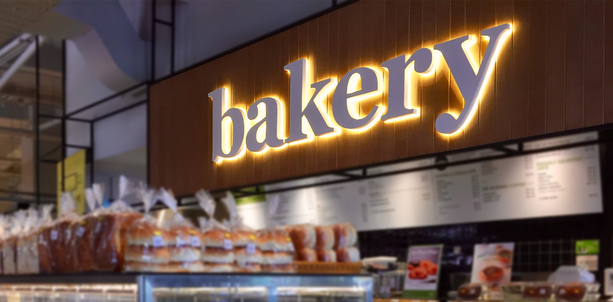 Modern bakery signage design in beige color with illumination featuring the word bakery