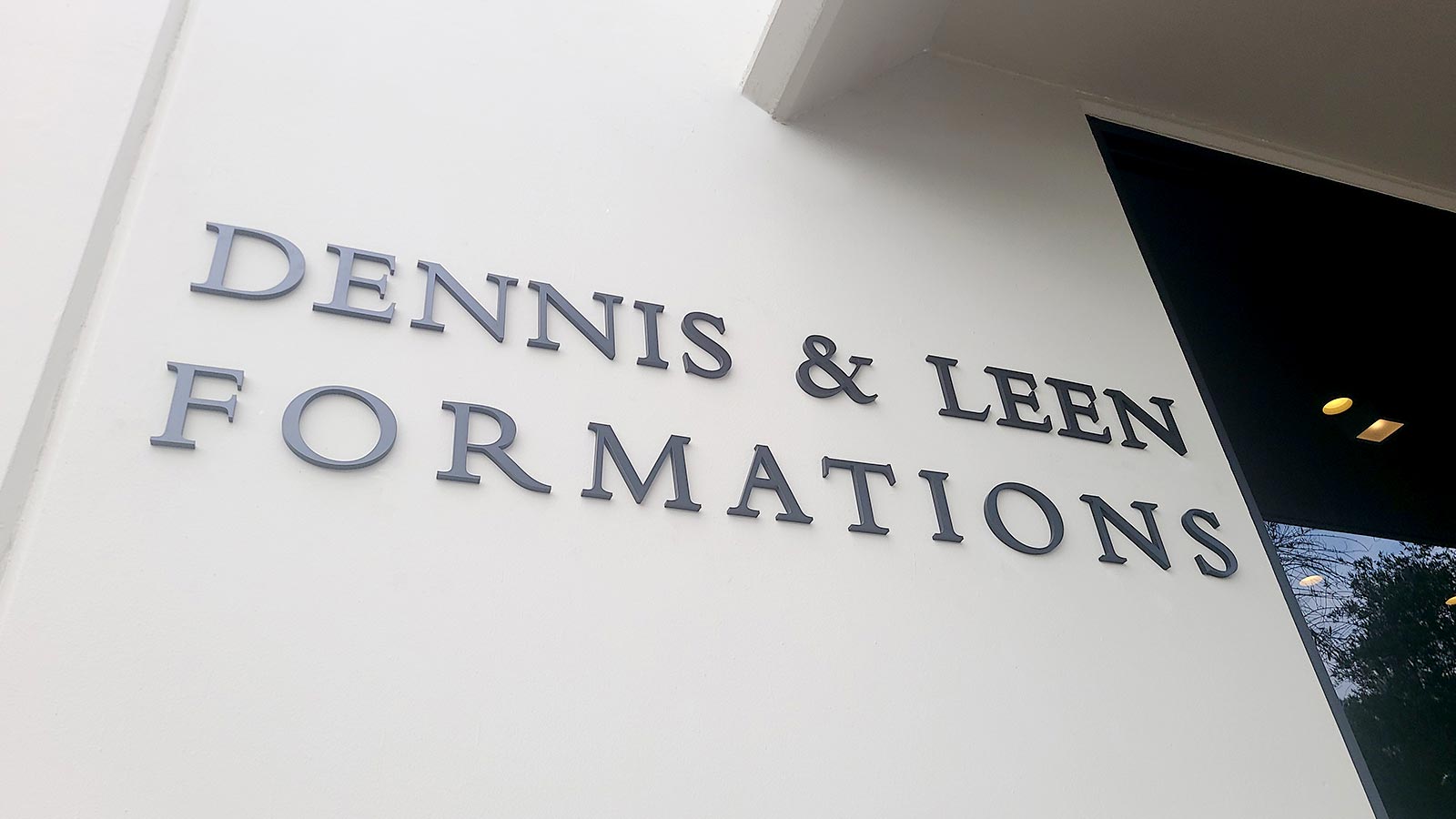 dennis and leen formations logo sign installed on the facade