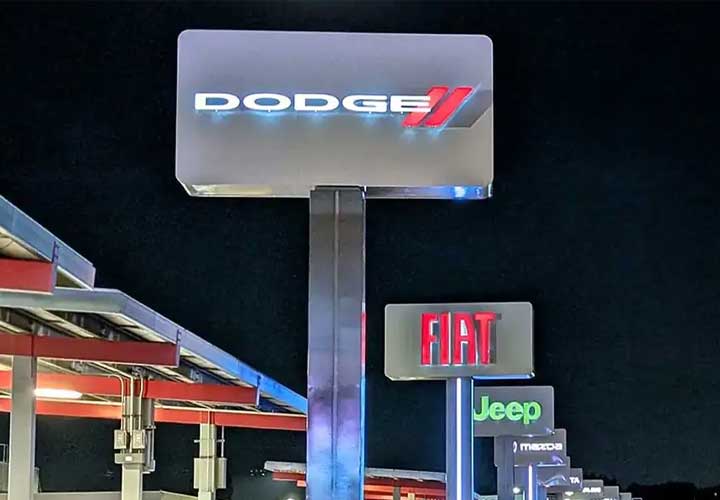 Large outdoor freestanding signs for a car dealership with Dodge, Fiat, and Jeep logos.