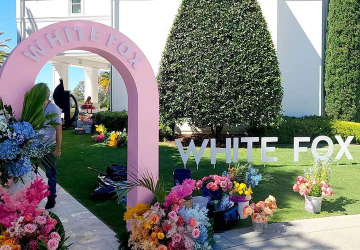 Pink freestanding signs with a White Fox cutout logo and floral designs.