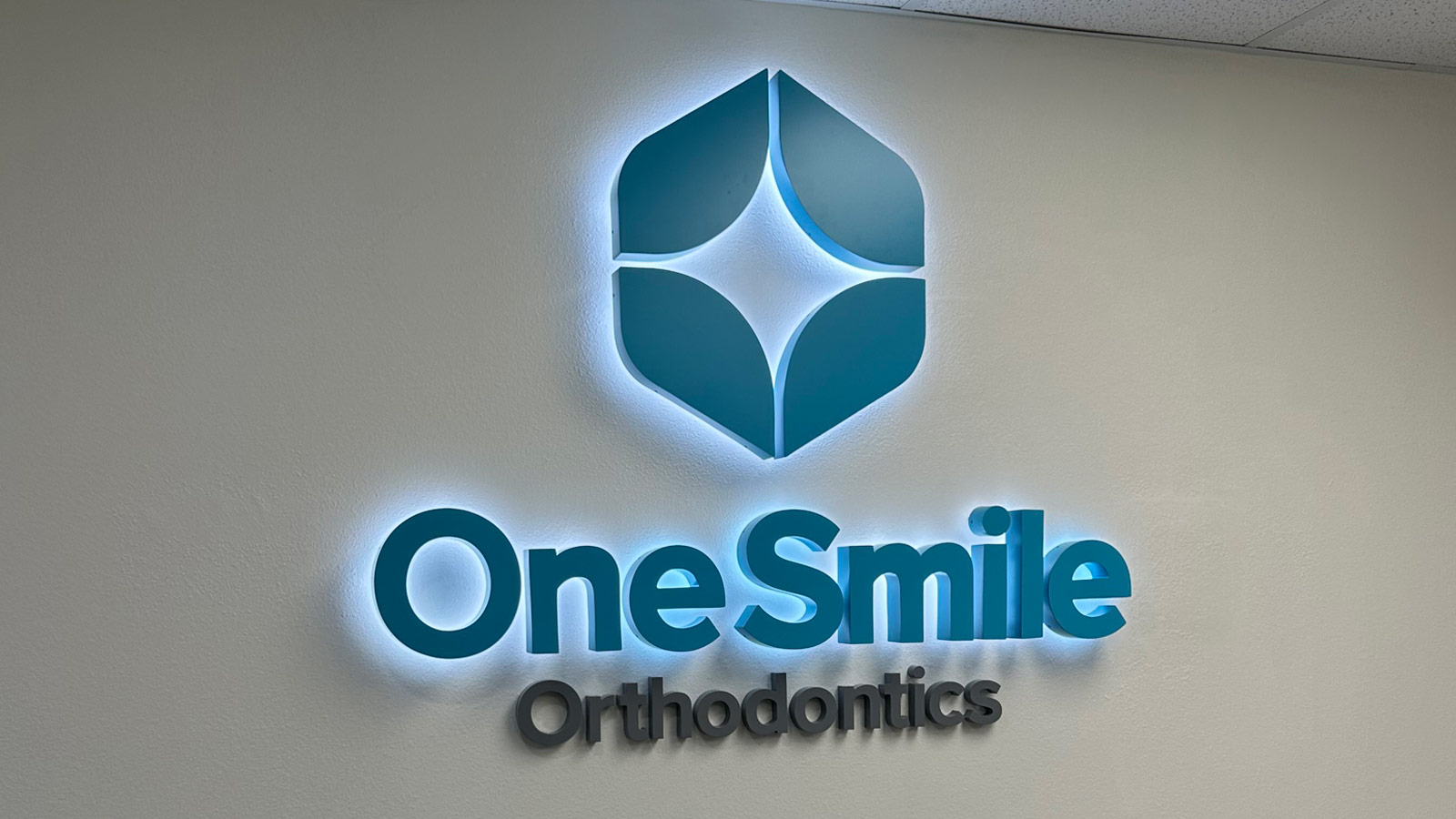 one smile orthodontics back-lit sign on clinic lobby wall