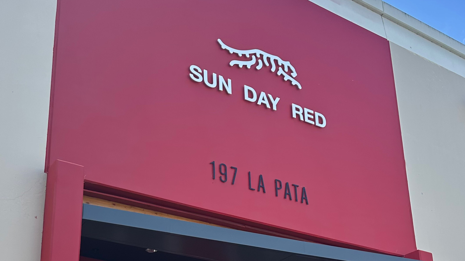 sun day red acrylic storefront sign on retail facade