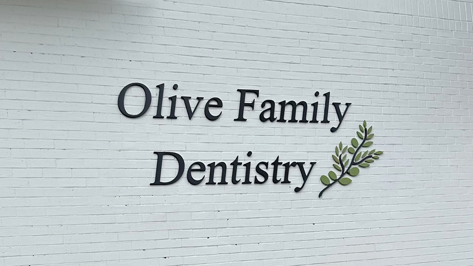 olive family dentistry acrylic letters on brick facade