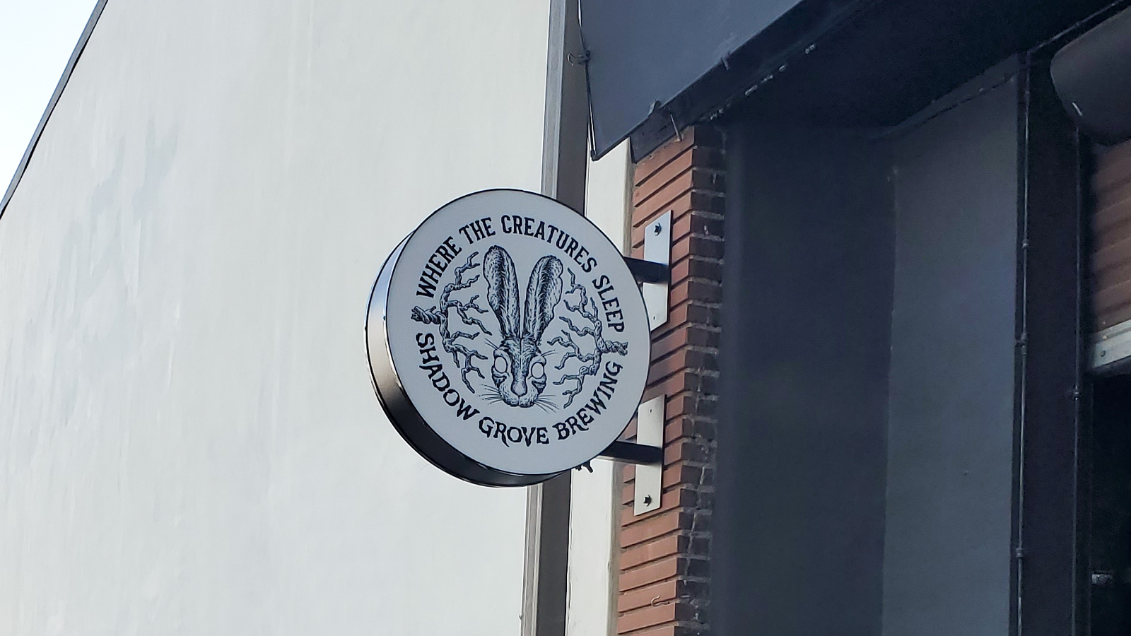 shadow grove brewing illuminated blade sign on bracket